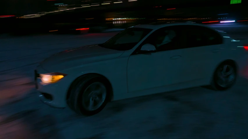 a white car with headlights on traveling at night