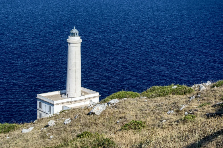 a lighthouse tower on a hill overlooking the ocean