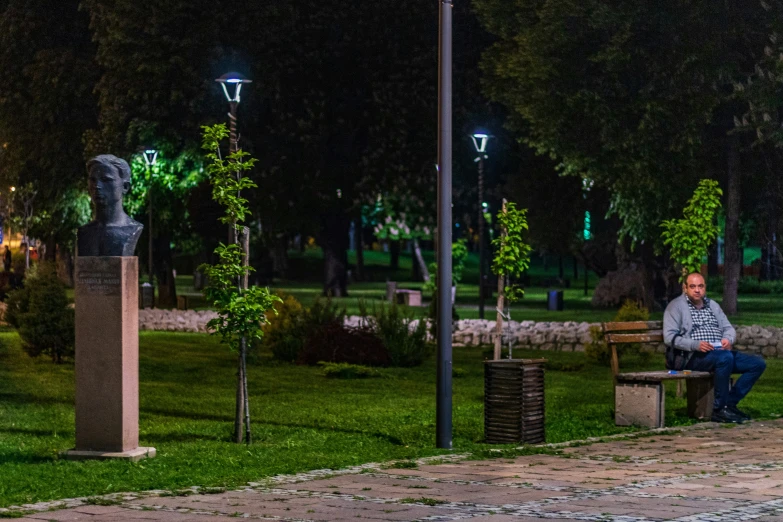 the man is sitting on the bench at the park