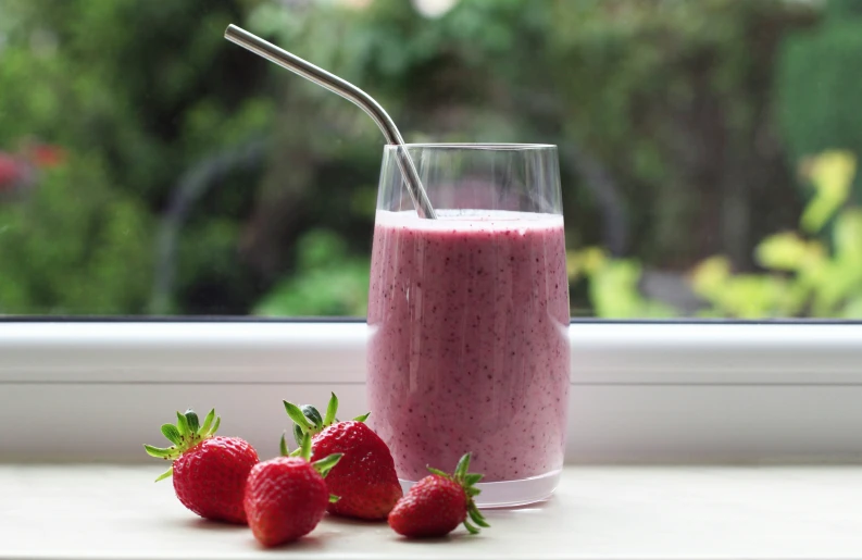 a glass and two strawberries on a table