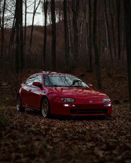 a red car parked next to some trees