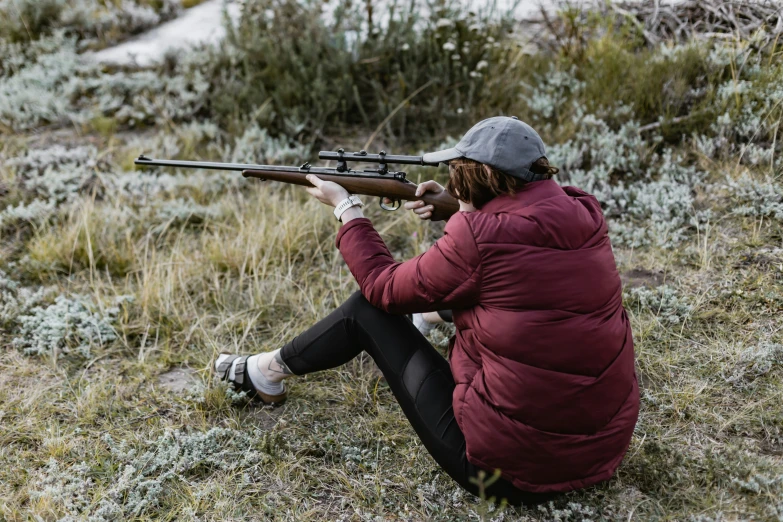 the person is aiming the rifle at the ground