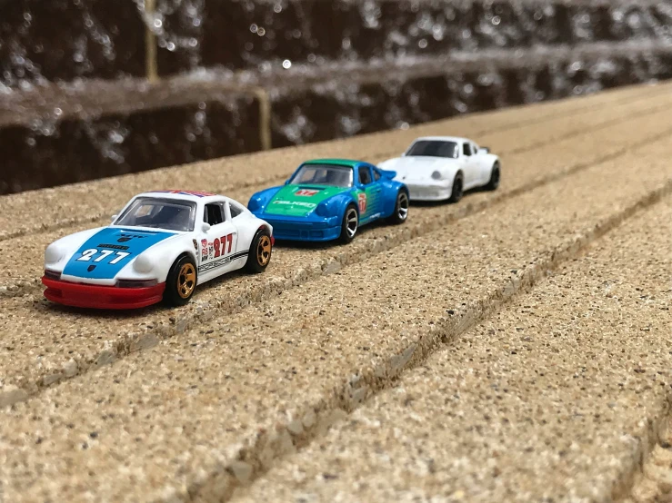 three toy cars one is red, white, and blue