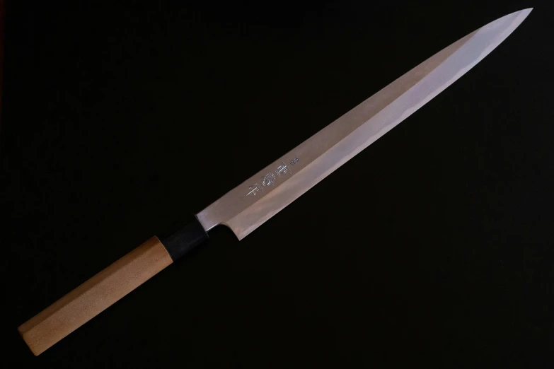 a chef knife with a wooden handle on a black background