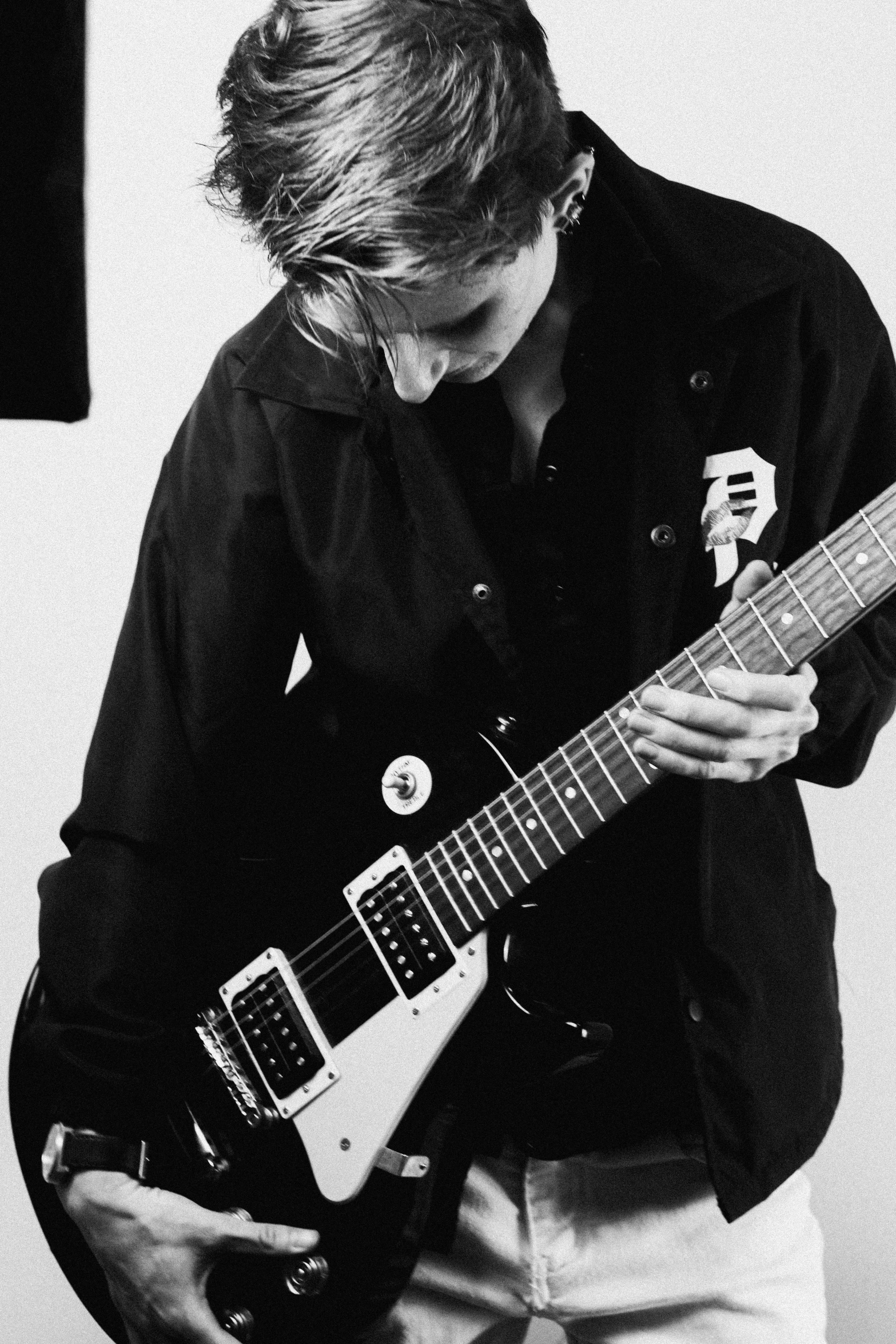 a man is playing guitar and leaning against the wall