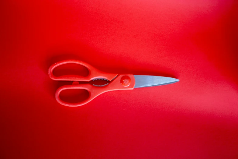 red scissors on a red surface with light coming through