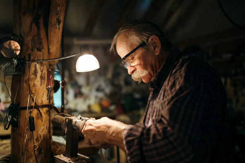 a man with glasses and mustache working on soing in a shop