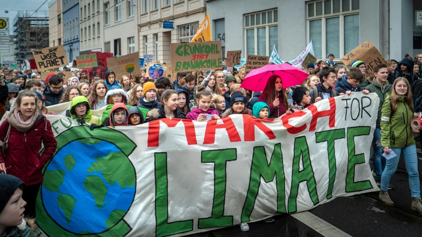 a large crowd is gathered behind a demonstration banner with a globe