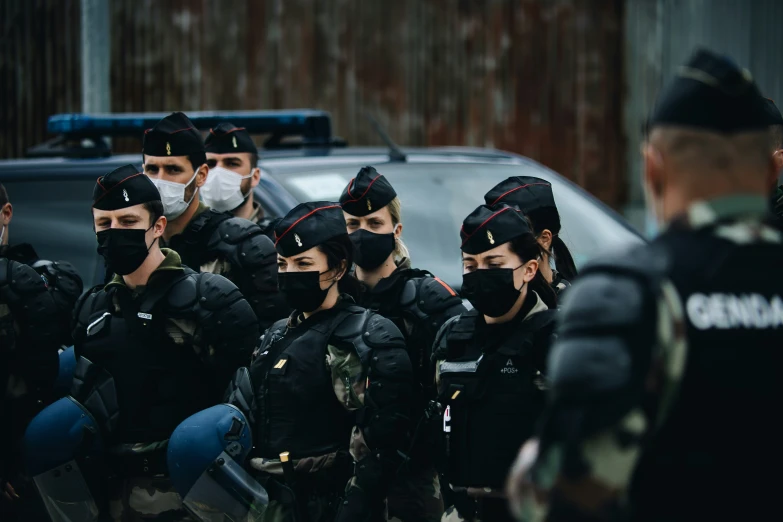 a group of cops in black jackets next to a police car