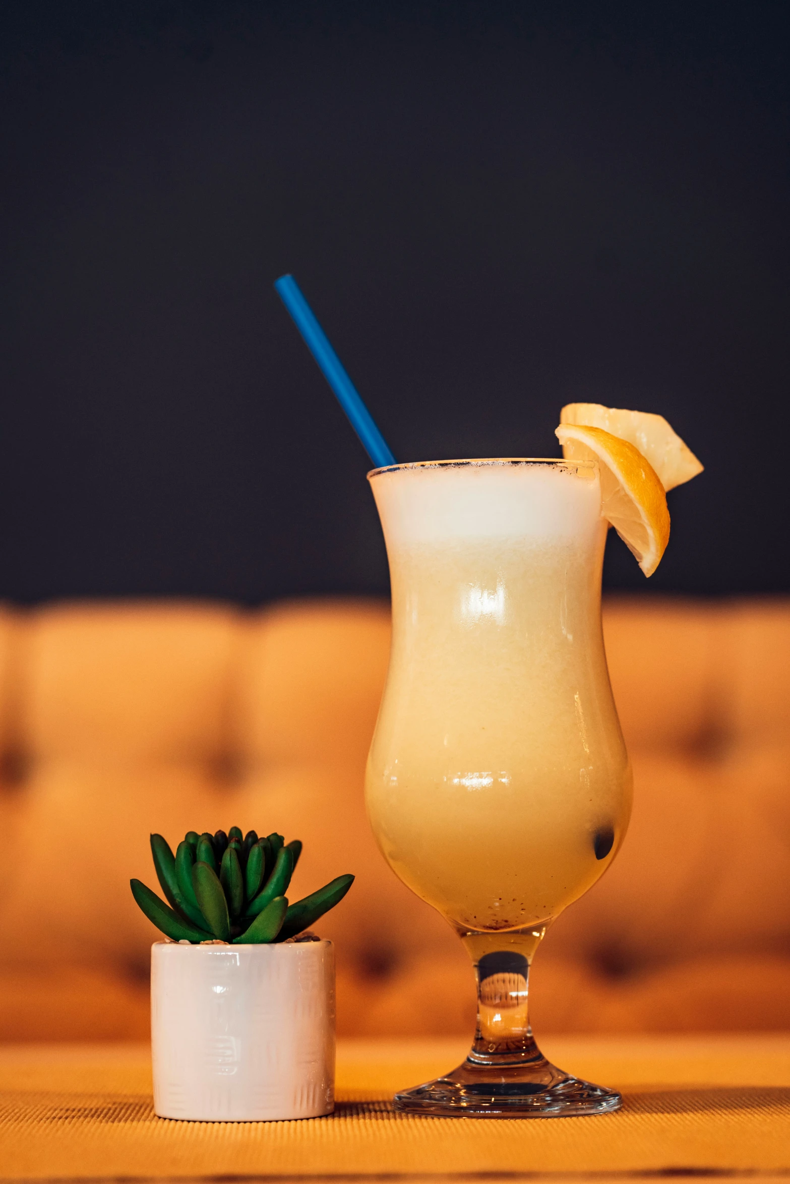 two glasses are sitting on a table one with a straw and one with lemon slices