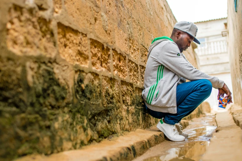 a man squatting on some bricks while cleaning his foot