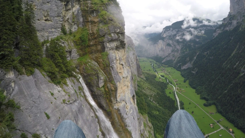 the view from the ground looks down at a waterfall, a road and a valley