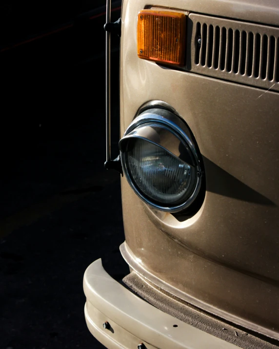 an old, beige car with its light on