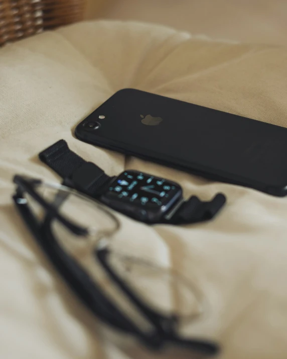 an ipod, glasses, and cell phone lying on the bed