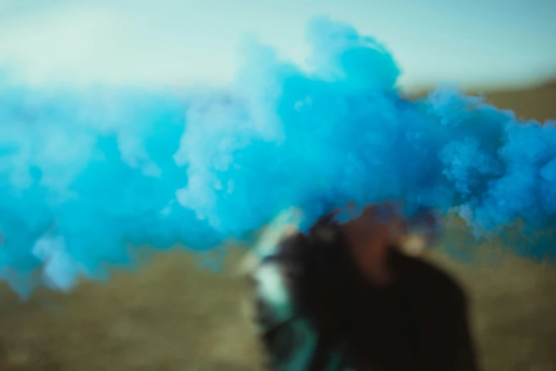 a blurry po of someone in a field with some blue smoke coming out of his head