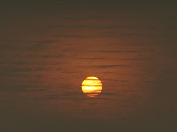 the sun just rising above the clouds on a dark day