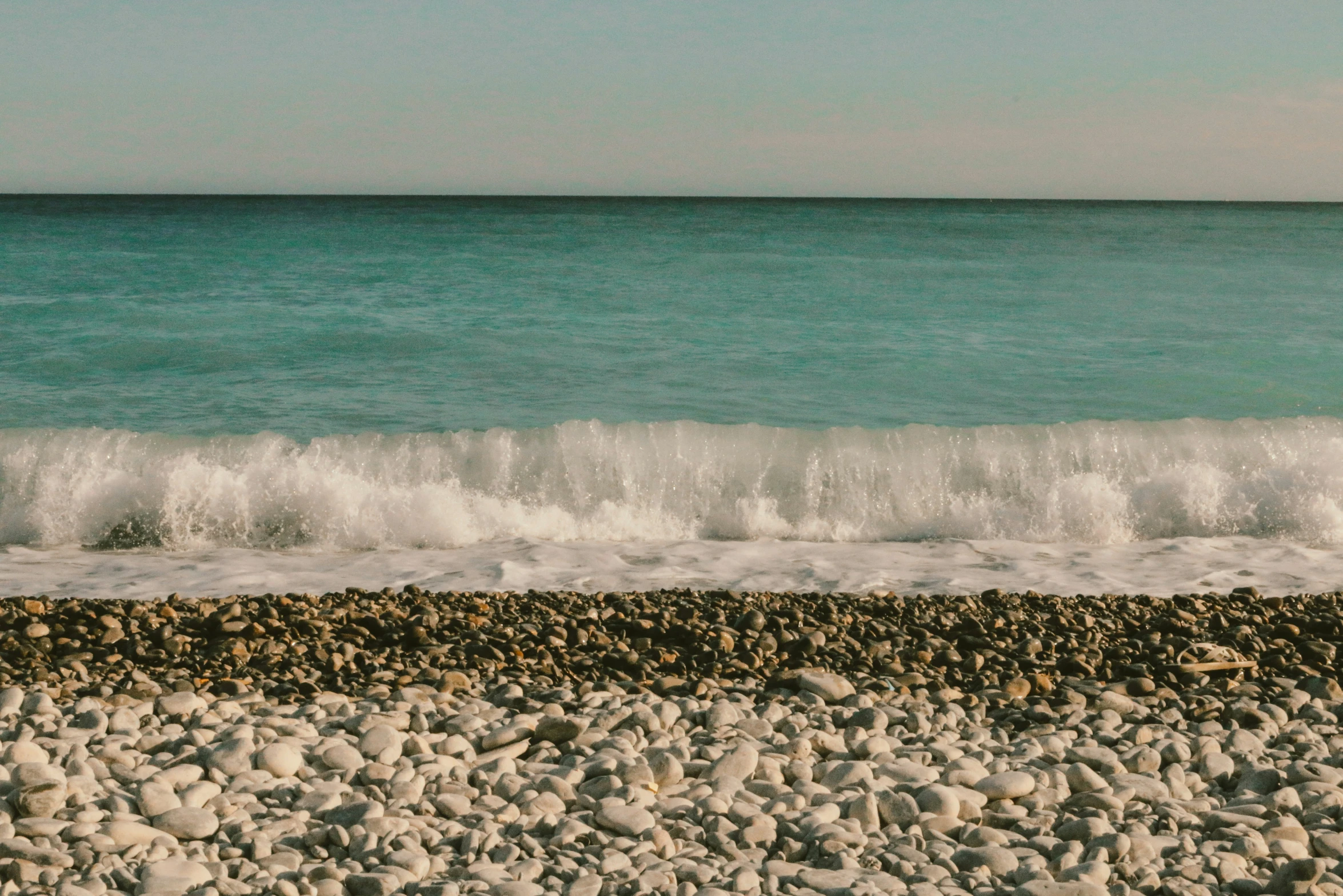 surfboard sitting on the rock in front of the beach