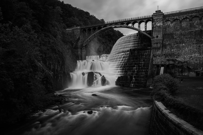 black and white pograph of a waterfall under a bridge