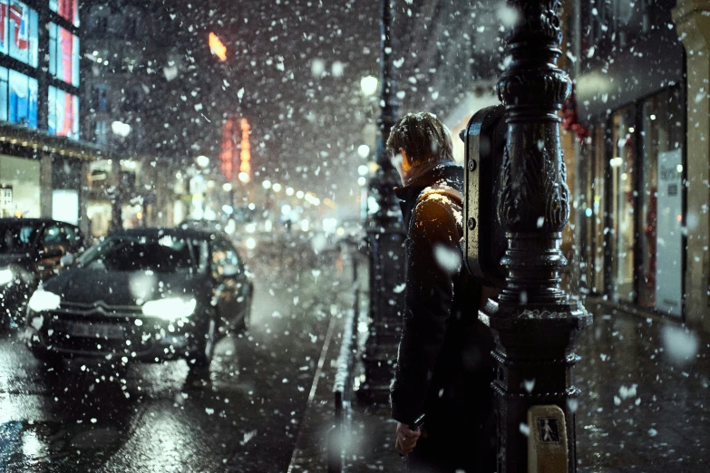 a woman walks along a street as it snows