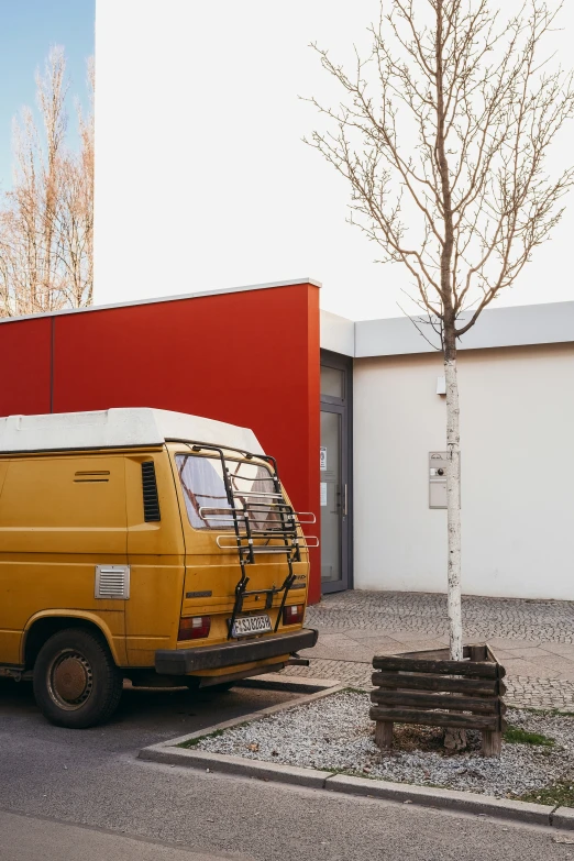 a yellow van with a bicycle on the front of it parked next to a tree