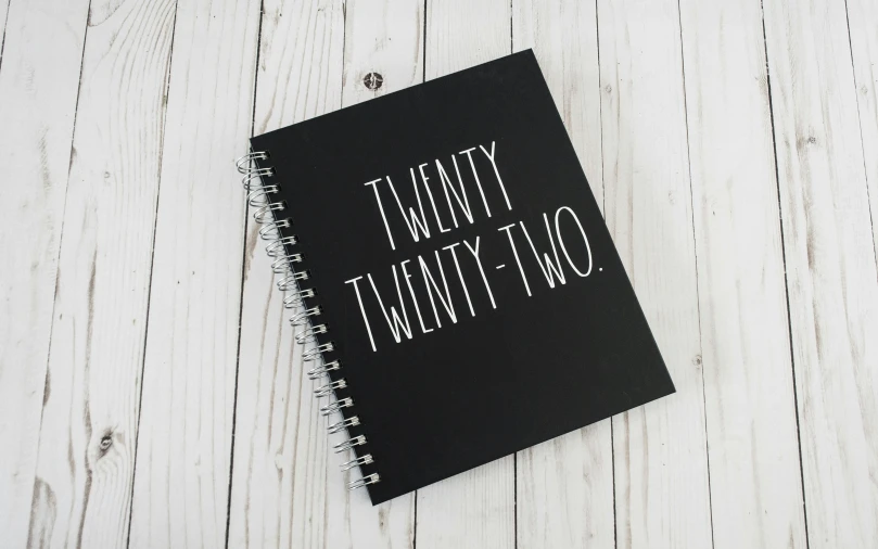 a black and white spiral notebook sitting on top of a wooden table