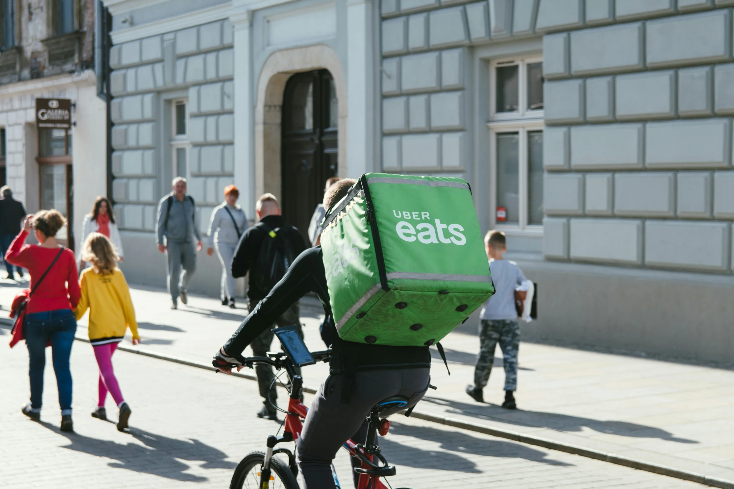 person riding bike while carrying a green food box on his back