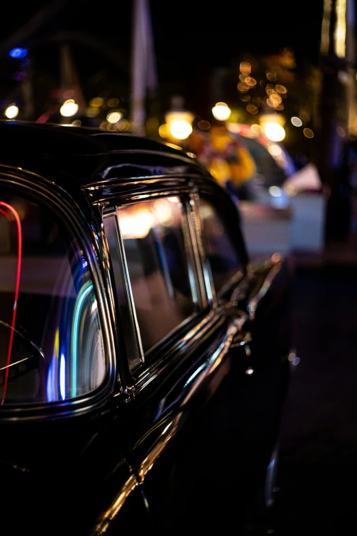 an old black car parked in front of a tall building at night