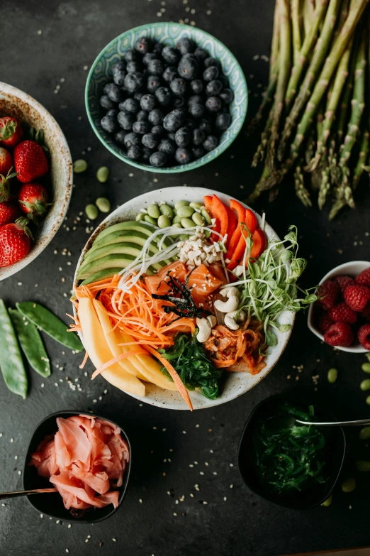 bowls filled with food and greens, fruits, and berries