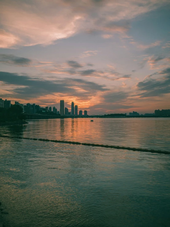 a body of water with the sun setting over the city