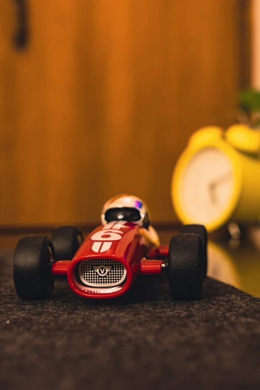 a red toy car is parked on the floor near a clock