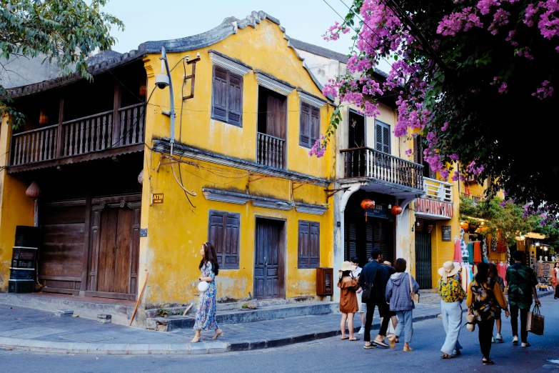 a group of people standing outside of a yellow building