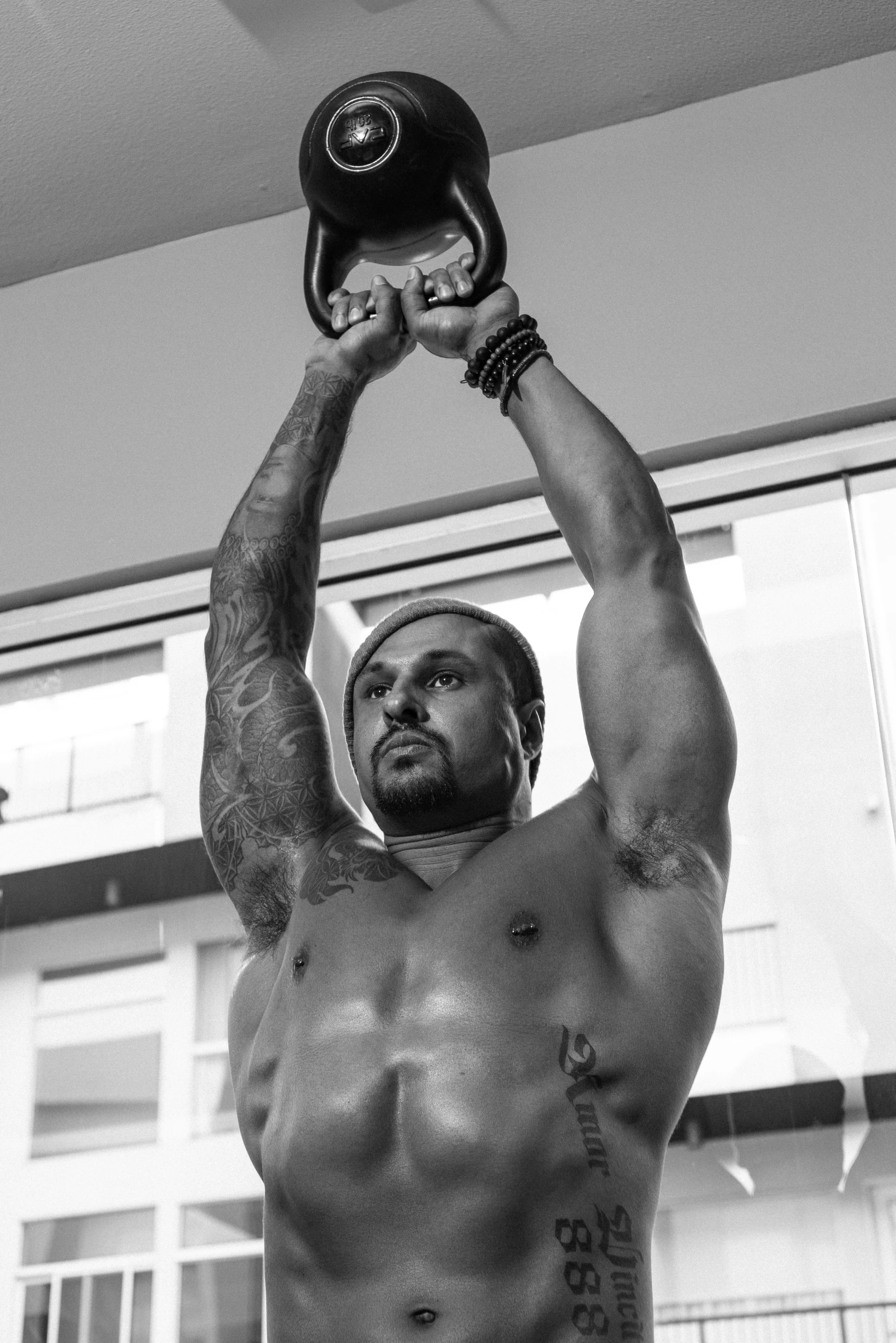 a shirtless man lifting a kettle up in the air