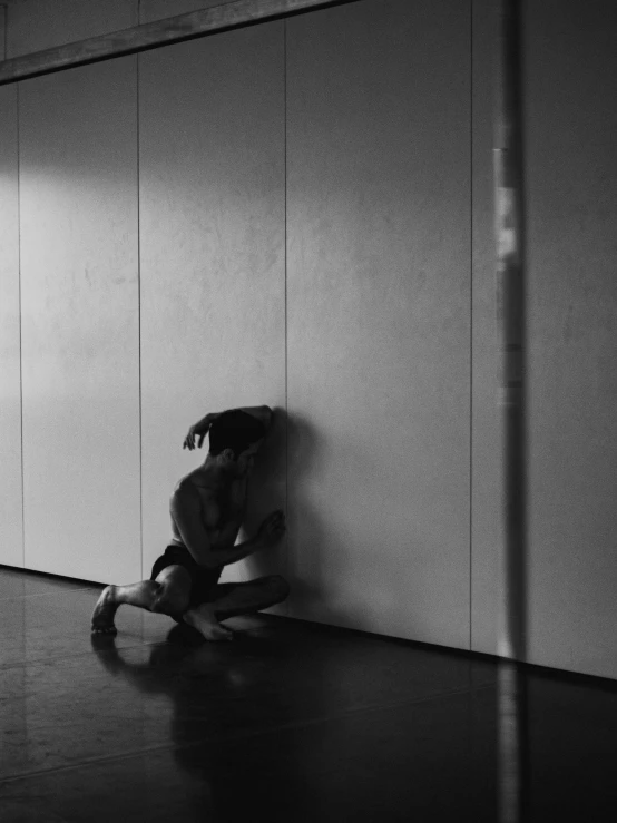 a person sitting down against a wall with his  out