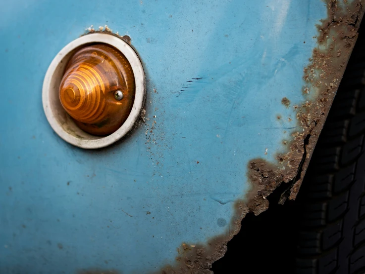 closeup of the front bumper and rusted fender of a vintage blue car