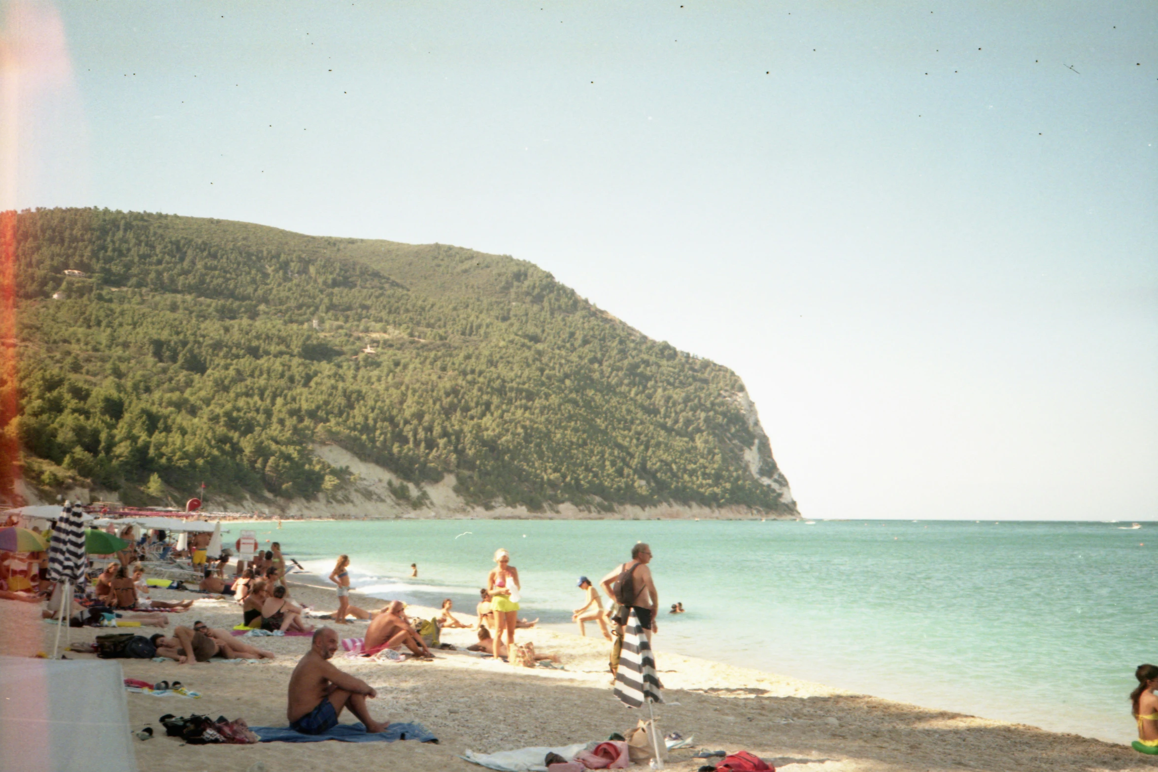 some people on a sandy beach and the water is blue