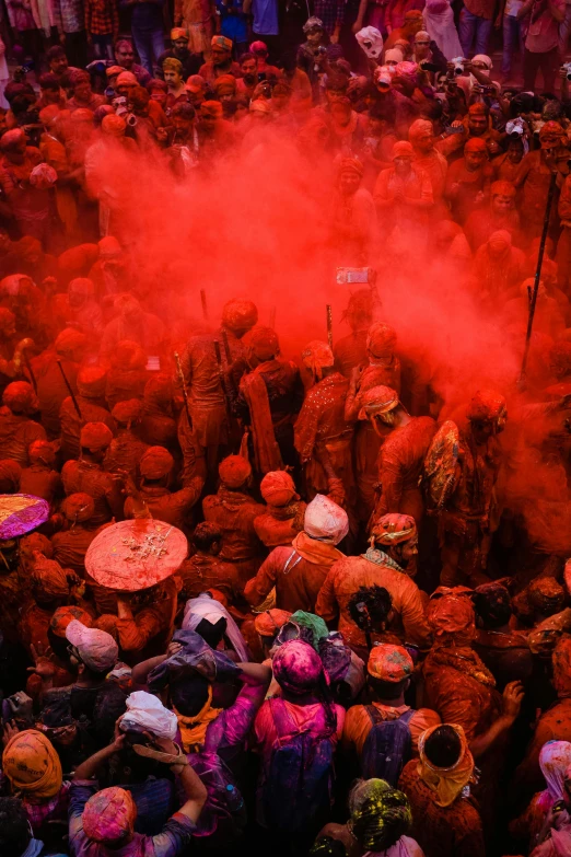 a crowd of people standing in the middle of an area with red powder