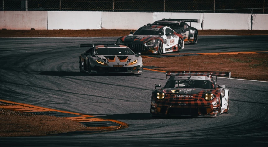 three racing cars driving side by side on a racetrack