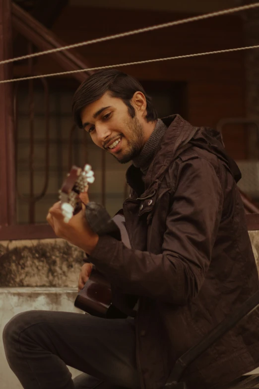 a man sits on a step and plays his guitar