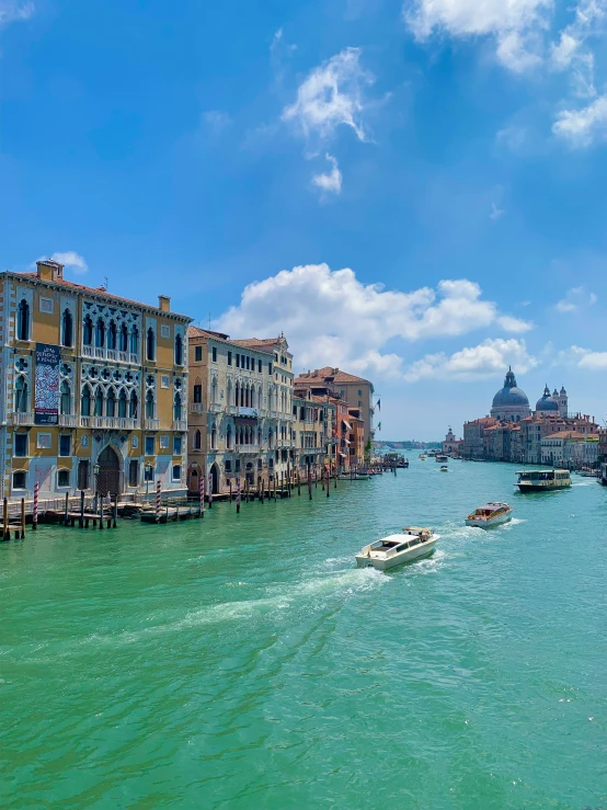 a boat traveling down a body of water with buildings and a tower