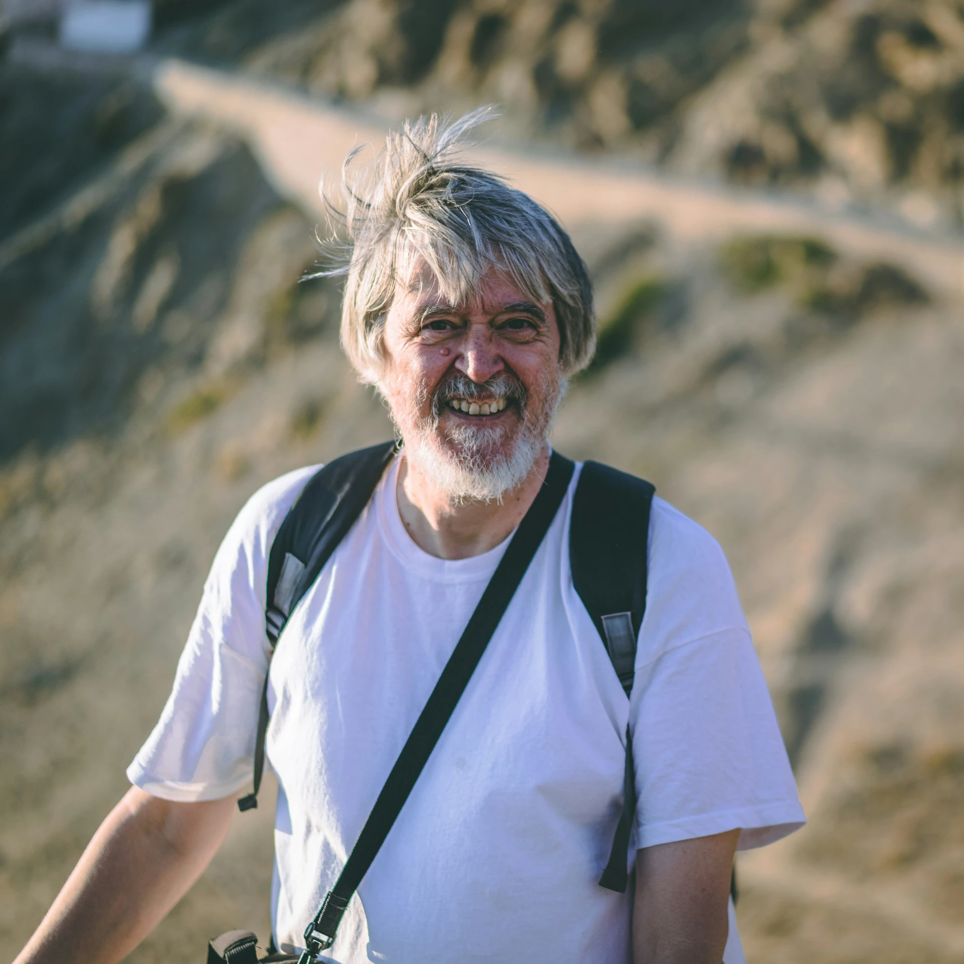 a smiling man with a camera next to a trail