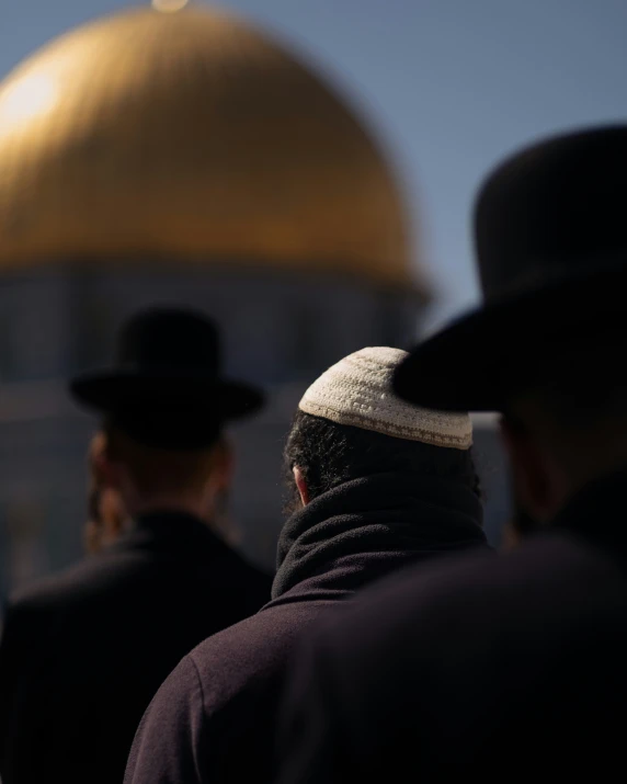 men in hats looking at the dome of the rock