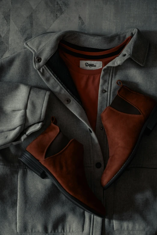 an orange and grey shoe, jacket, and shirt on top of a bed