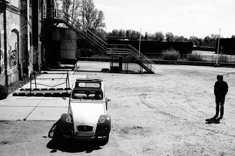 a man standing in the dirt near an old volkswagen car