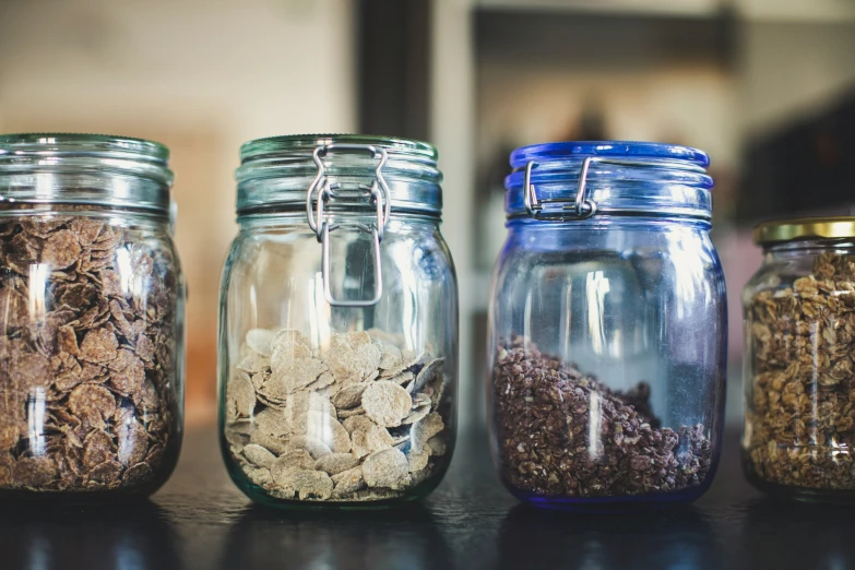 three jars with seeds and granola on a table