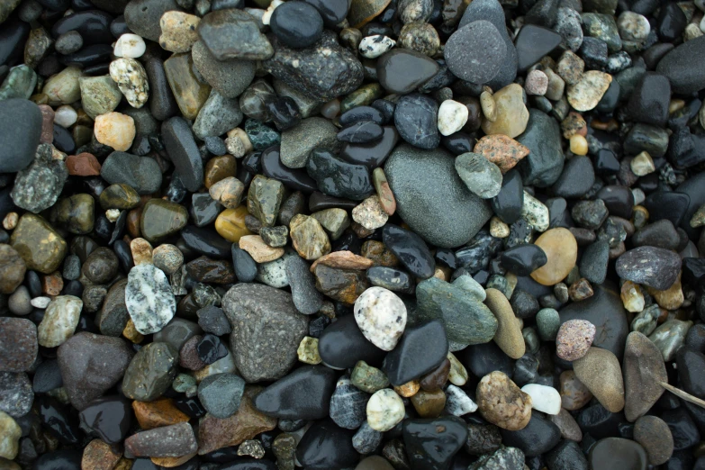 various colored rocks on a black sand area