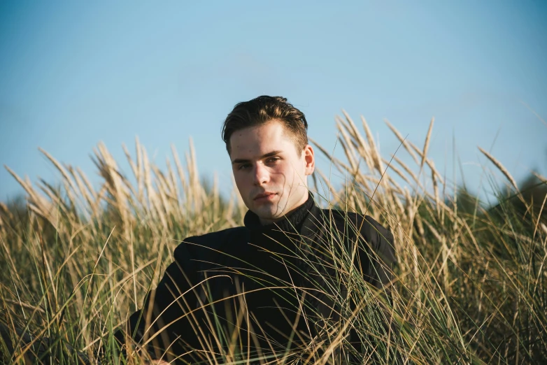 man in black shirt standing near tall grass