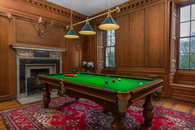 a room with a pool table and three lamps on the ceiling