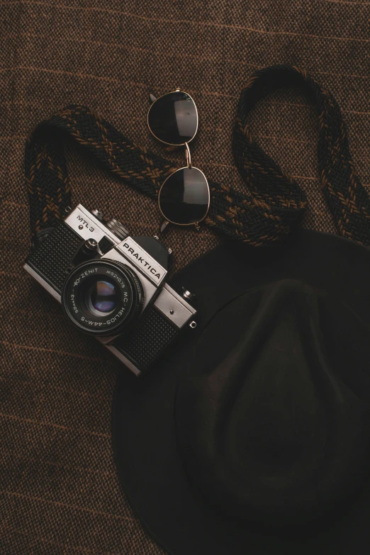 an old camera sitting next to a hat and sunglasses