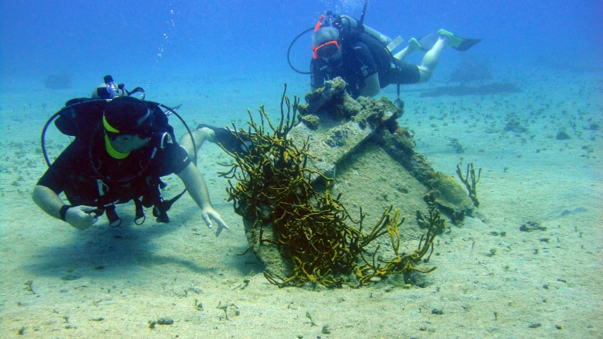 a man and woman scuba near a sunken structure