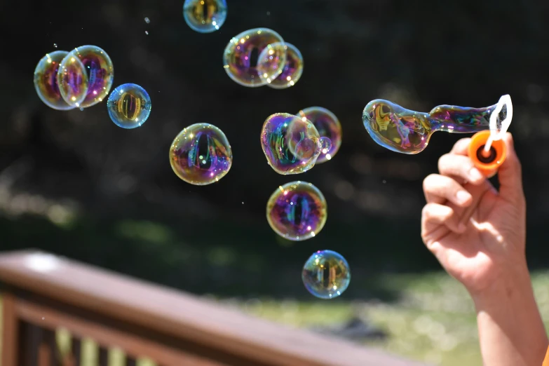 someone's hand holding a pen and bubbles fly in the air